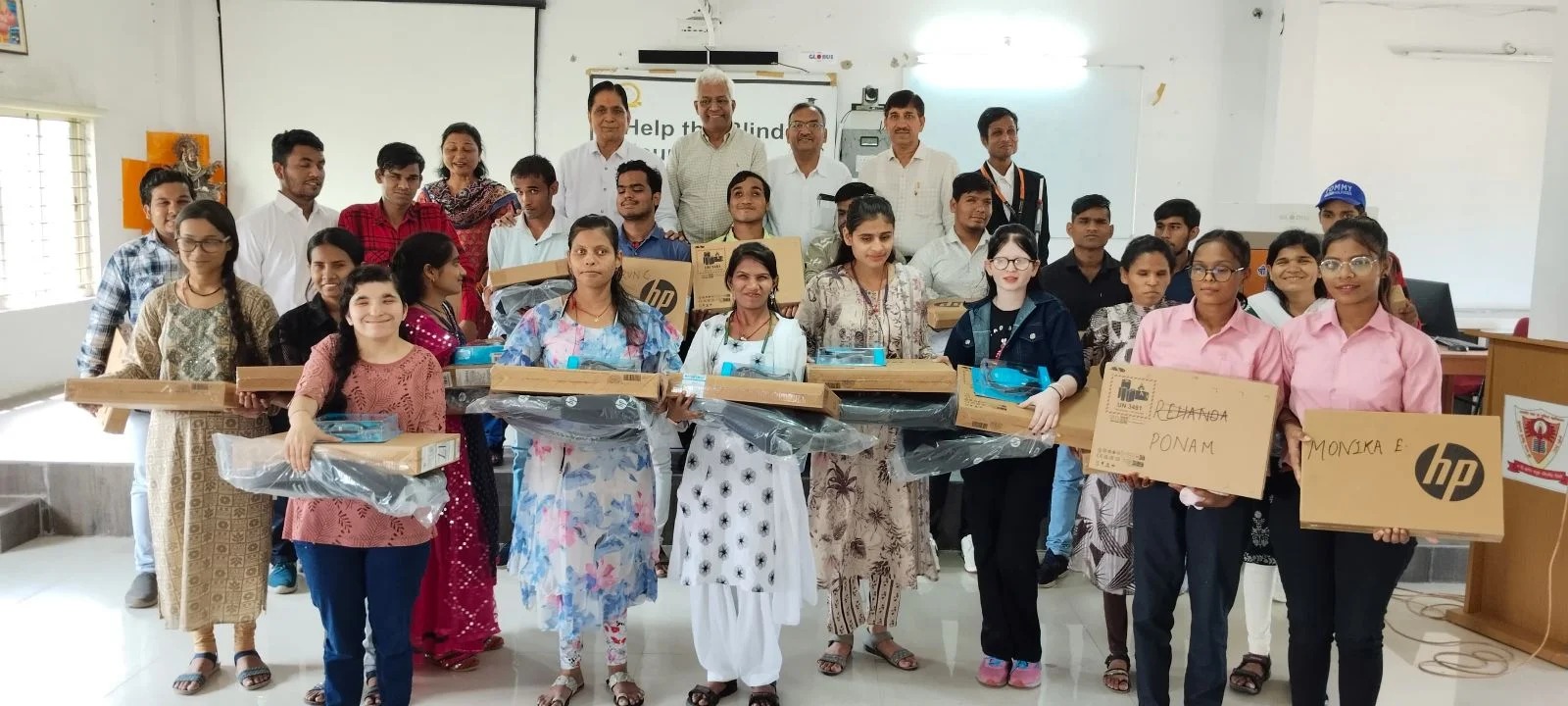 Group photo of visually impaired students holding laptops with HTBF Trustee Mr. Nataraj Sankaran and other dignitaries, taken during the laptop distribution in Indore.