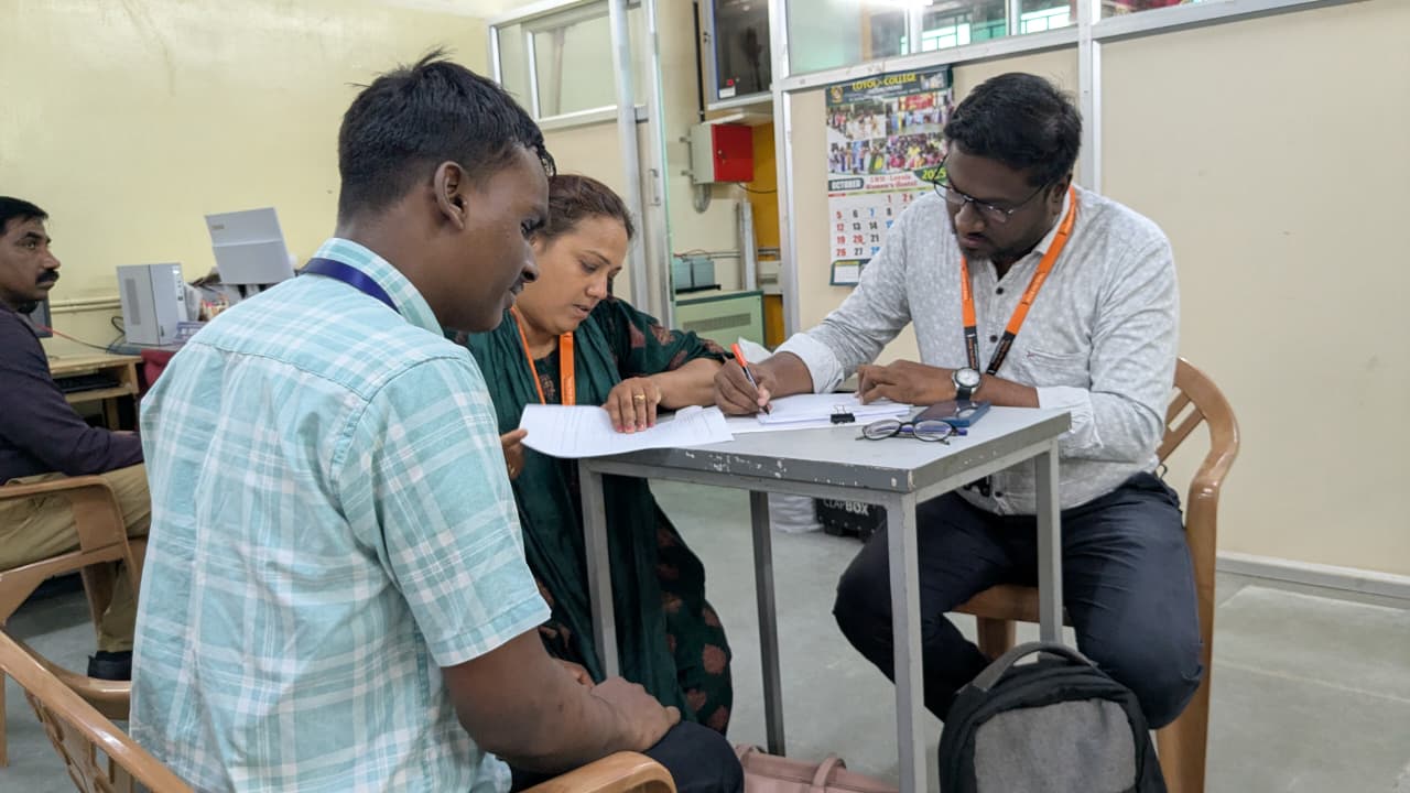 HTBF Staff Interacting with a student during the scholarship drive, filling out application forms at a desk.