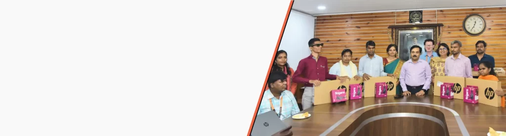 Dignitaries from Maharaja Sayajirao University and HTBF stand with visually impaired students holding laptops during the laptop distribution program.