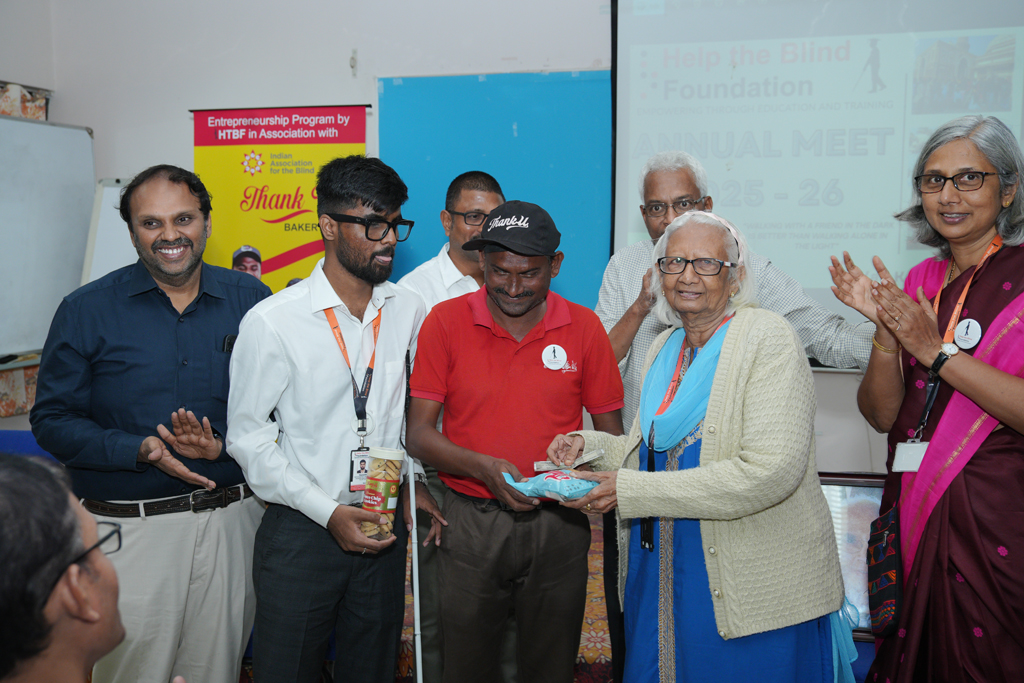 HTBF Co-Founder Mrs. Niti Patel is purchasing an item from a man on stage while other team members stand beside them clapping